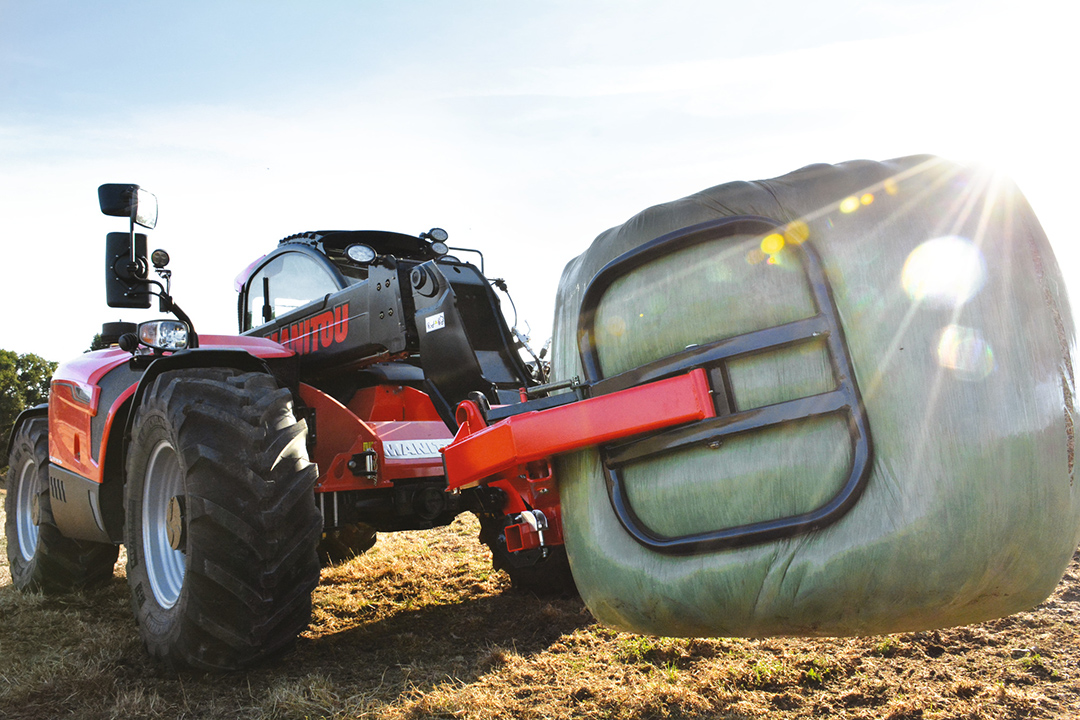Manitou MLT737 telehandler with bale clamp attachment holding a wrapped bale