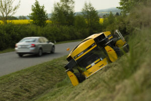 spider mower cutting grass on the side of a road